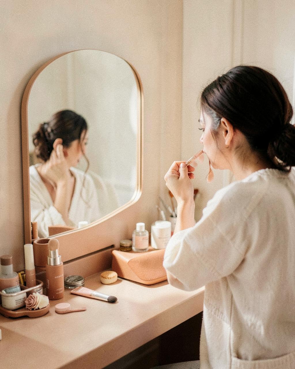 Creator applying skincare at a warm-toned vanity mirror